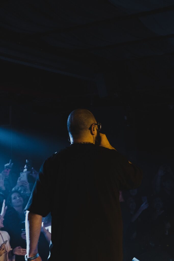 A musician singing into a microphone while facing a concert audience.