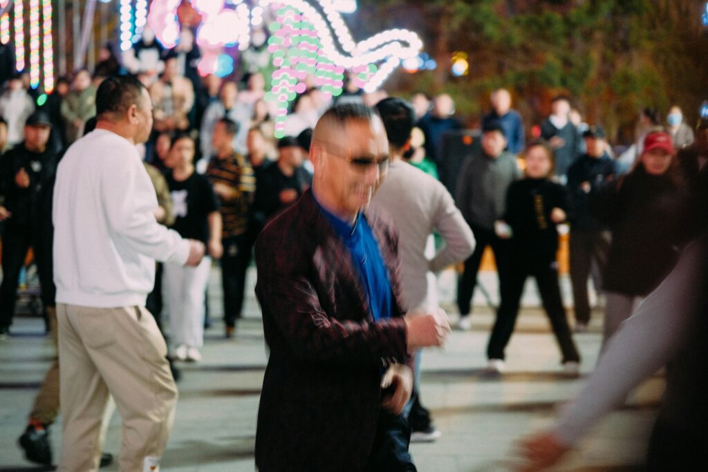 People dancing outdoors at night beneath city lights.