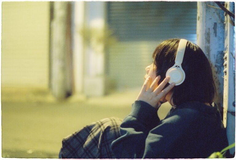 A woman listening to music through headphones in an urban night setting.