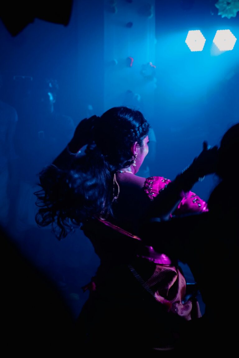A person dancing beneath blue and pink lights at night.