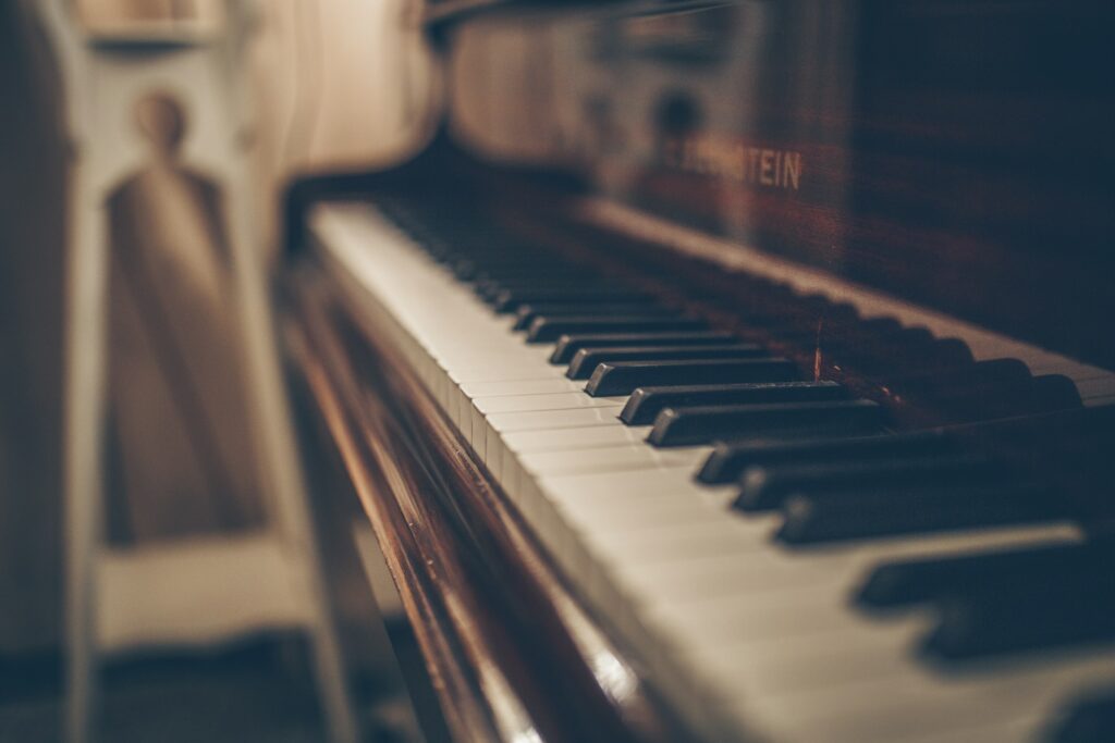 Piano keys in close-up with a person softly blurred in the background.